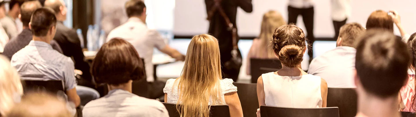 Semianrraum mit Reihen von sitzenden Menschen die auf die einem Vortrag zuhören